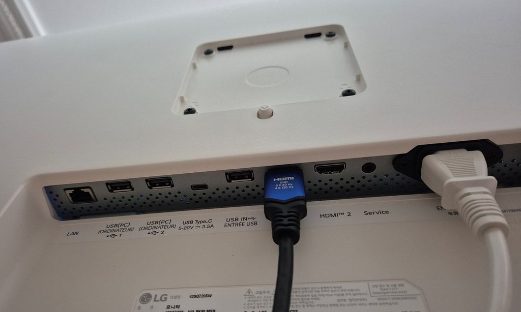 모니터 후면 단자. 왼쪽부터 유선랜, USB, USB-C, USB, HDMI 1번에 케이블이 꽂혀 있고 HDMI 2와 전원 케이블이 보인다. 위쪽에는 베사홀, 아래 라벨에 모델명 43SQ720SW가 있다.